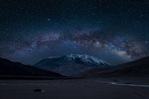 A celestial dance unfolds over Hanle, Ladakh, as the fully bow-shaped Milky Way arches above a round peak. The night sky comes alive with the cosmic embrace of stars, offering a glimpse into the mesmerizing beauty of Ladakh's nighttime realm.