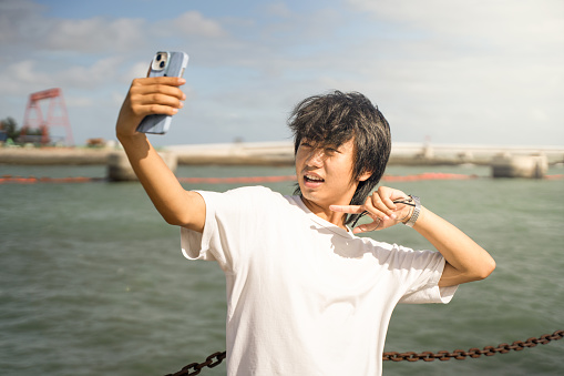 A boy who travels to the seaside and takes a happy selfie
