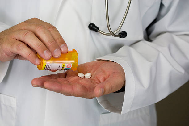 Doctor dispensing two tablets from a bottle stock photo