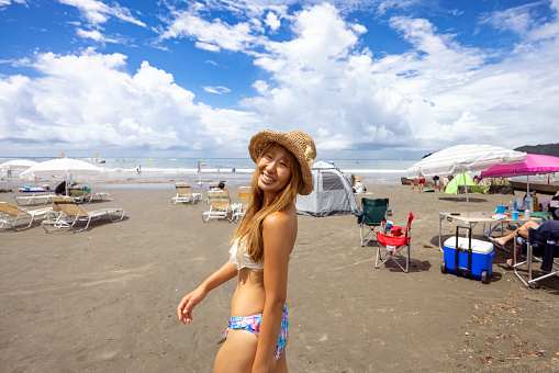 Happy woman in bikini walking on summer beach