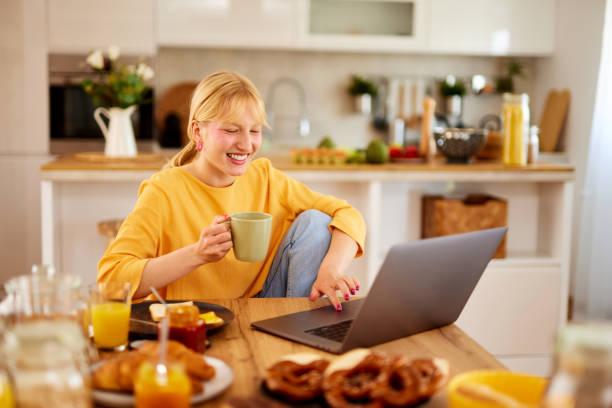 istock Young woman drinking coffee and working on her laptop over breakfast at home 1601071077
