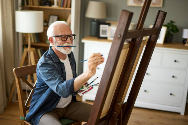 istock Elderly man painting on a canvas at home 1601076995