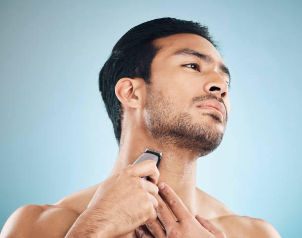 istock Face, shaving and electric razor with a man in studio on a blue background for personal hygiene, skincare or grooming. Beauty, wellness or cosmetics with a young male in the bathroom for hair removal 1601083721