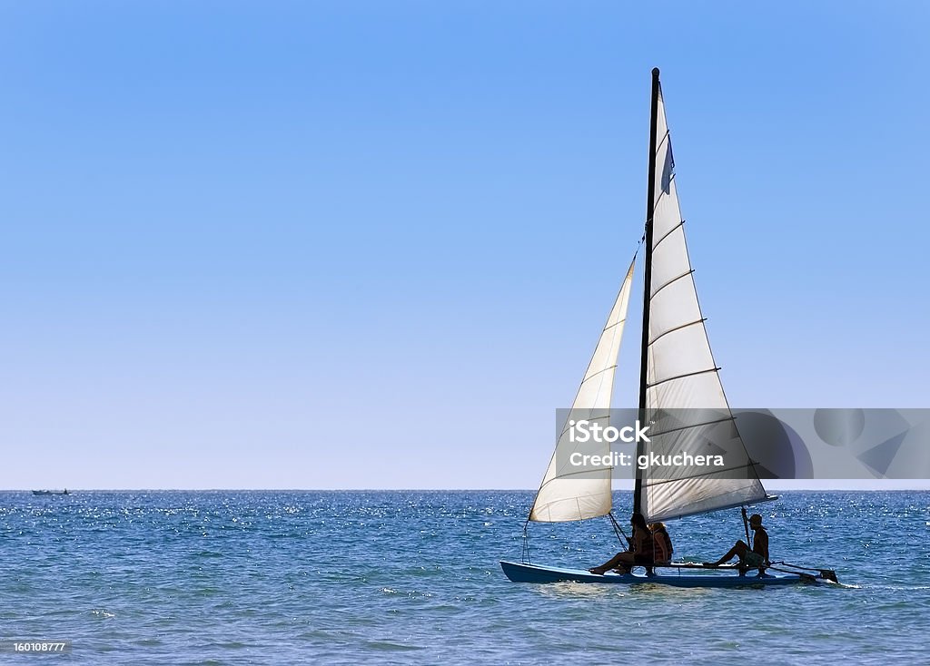 Sailing Out to Sea Two women and man sail catamaran sailboat out into Pacific Ocean Mazatlán Stock Photo