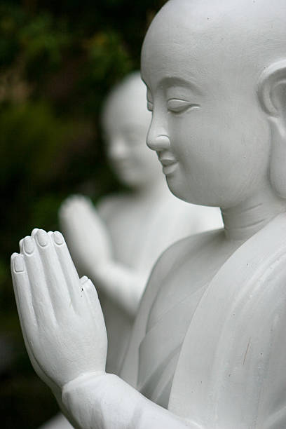 Closeup of Buddha with devoted expression and folded hands stock photo