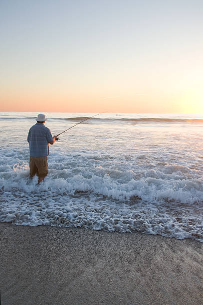 Beach Fishing Fisherman on an ocean beach fishing. sea fishing stock pictures, royalty-free photos & images