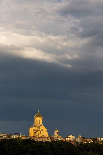 A vertical of a church in sunlight under a cloudy sky in Zizi, Tbilisi, Georgia