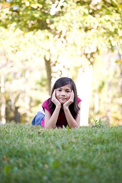 istock Little girl lying down on grass, chin in hand 160110722