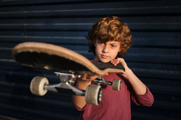istock Little skater examining skateboard against wall 1601111650