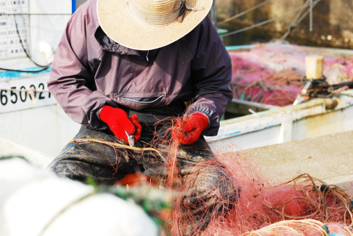 Fisherman repairing a fishing net.