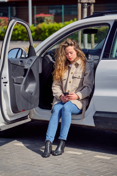 istock Young woman using smartphone and sitting in car 1601116154