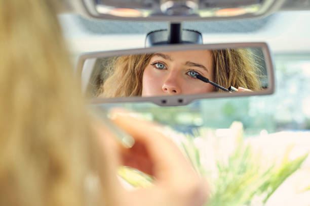 istock Attractive woman applying mascara and looking in rearview mirror 1601116721