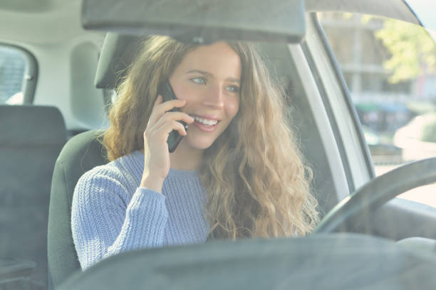 istock Smiling woman talking on smartphone in car 1601117864