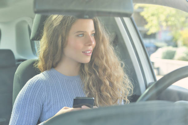 istock Beautiful woman using smartphone in car 1601121414