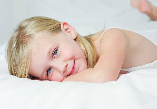 Little girl laying on a bed stock photo