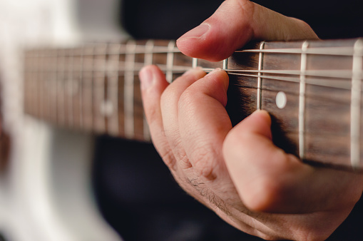 close-up male hand doing bending technique on electric guitar, focus on left hand.
