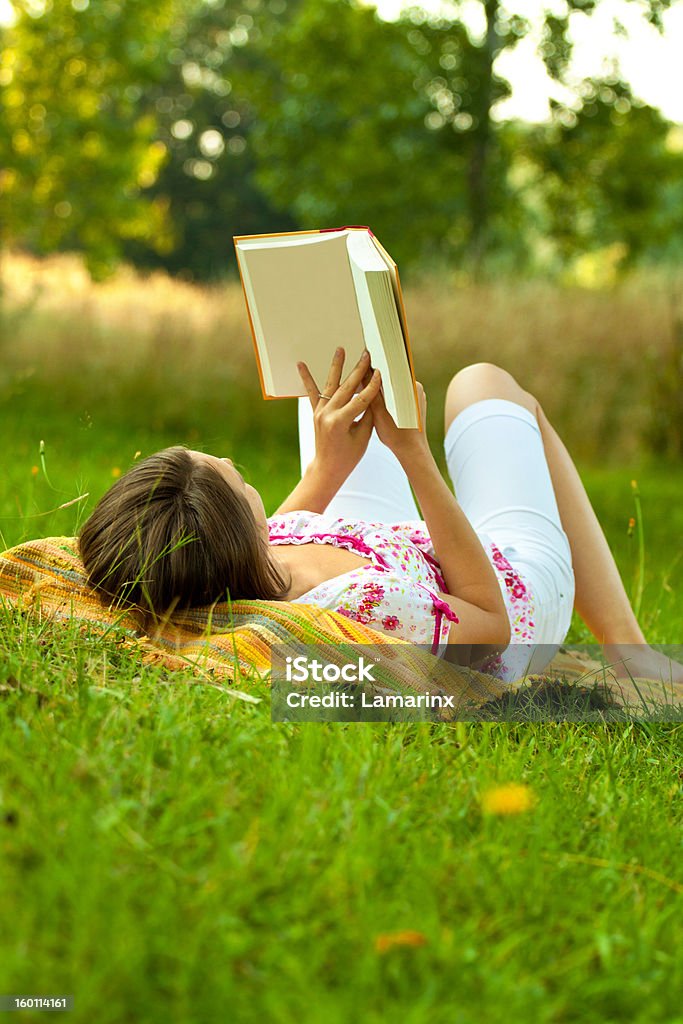 Beautiful woman relaxing in the park Beautiful woman relaxing in the park with a book. Vertical shot with copyspace. Adult Stock Photo