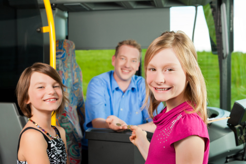 Children boarding a bus and buying a ticket