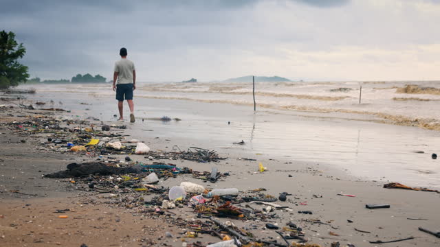 a man walking on Endless plastic pollution from sea shore on beach. Garbage Washed Ashore