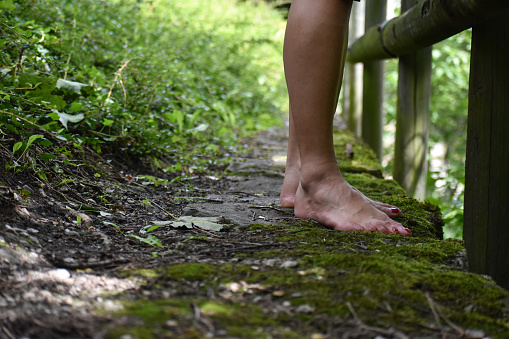 A female is walking barefoot at a mossy forest