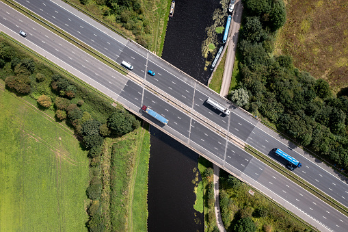 Aerial view directly above a busy UK motorway passing over a river or canal bridge in the countryside