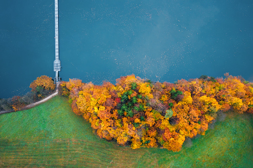 Aerial view on footpath and bridge over the beautiful blue lake. Trees are in autumn colours.