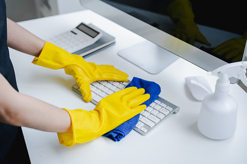 Young woman using a computer keyboard cleaning cloth to disinfect the office
office cleaning staff cleaning maid