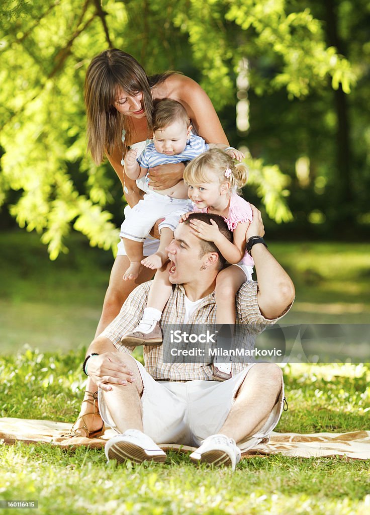 FAMIGLIA FELICE giocando nel parco - Foto stock royalty-free di Adulto