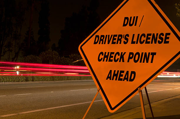 OrangeCheckpointSign Orange DUI 'sobriety' and driver's license checkpoint ahead sign along side of road with car light trails in background driving under the influence stock pictures, royalty-free photos & images