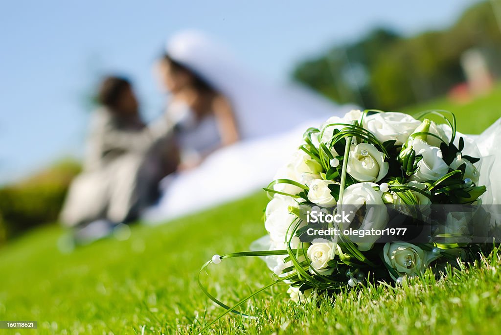 wedding bouquet bridal bouquet of white roses on a green meadow and blurred newlyweds Beauty In Nature Stock Photo