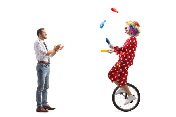 full length profile shot of a young man watching a clown on a trycicle and clapping with hands - unicycle men young adult standing imagens e fotografias de stock