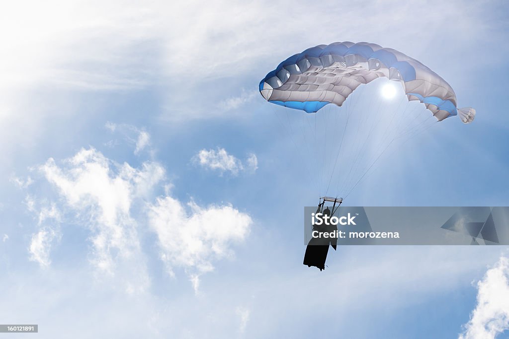 Paracadute in cielo sotto i raggi del sole, skydiver sagoma in tuta alare. - Foto stock royalty-free di BASE jumping