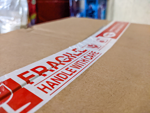 Close up of fragile handle with care label attached to cardboard