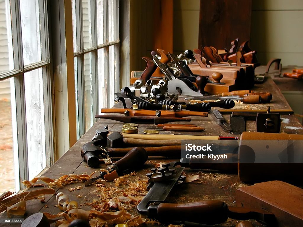 Woodworking tools and wood shavings on table near window Old carpenter's tools in front of window. Woodturning Stock Photo