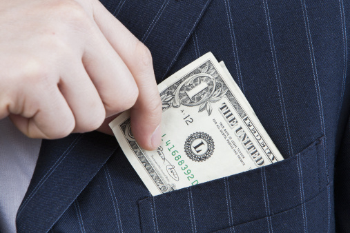 close-up of businessman slips money into suit front pocket