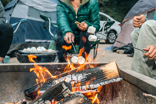 A group of friends roasting marshmallows on a campfire at their campsite in Big Sur, California.