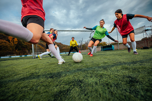 A low wide angle shot closeup of female football players leg shooting the ball on the goal.