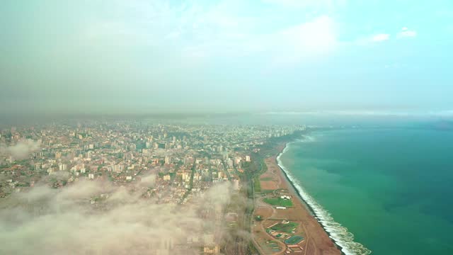 Aerial view of Lima between the clouds, view flying over the tops of the clouds and unveiling the city.
