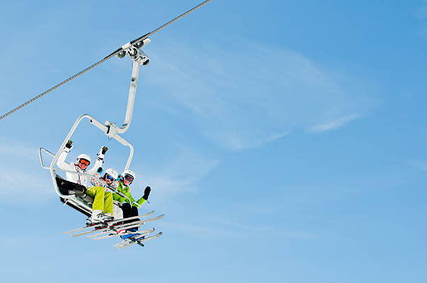 Trio of skiers riding on a ski lift Happy skiers on ski lift - space for text ski lift photos stock pictures, royalty-free photos & images