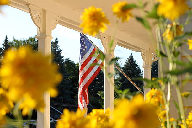 US Flag On Porch Traditional photo of a United States flag hanging on a 19th century style porch. american flag flowers stock pictures, royalty-free photos & images