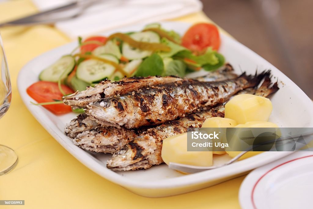 Grilled fish on dinner plate with salad Grilled sardine with potato and salad Portuguese Culture Stock Photo