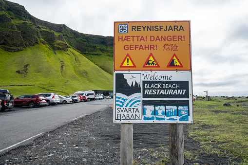 Vik, Iceland - July 8, 2023: Sign reminding tourists and visitors of the dangers of sneaker waves at Reynisfjara Black Sand Beach.