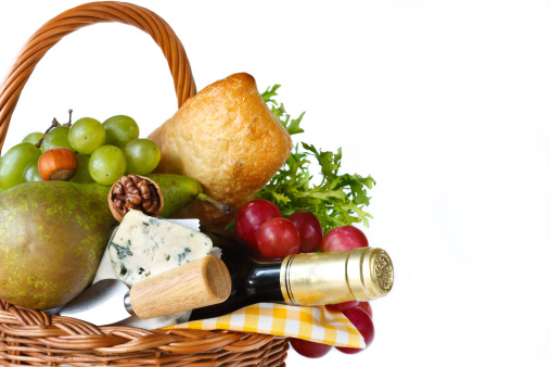 Wine, ciabatta, cheese and fruits in a wicker basket for picnic.