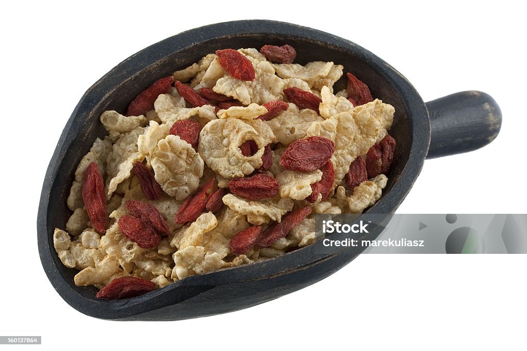 scoop of rice cereal with Tibetan wolfberries light rice cereal with red dried Tibetean goji berries (wolfberry) on a rustic wooden scoop isolated on white Berry Fruit Stock Photo