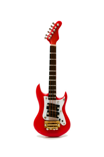 A red electric guitar isolated on white. The miniature musical instrument is standing against the white background.