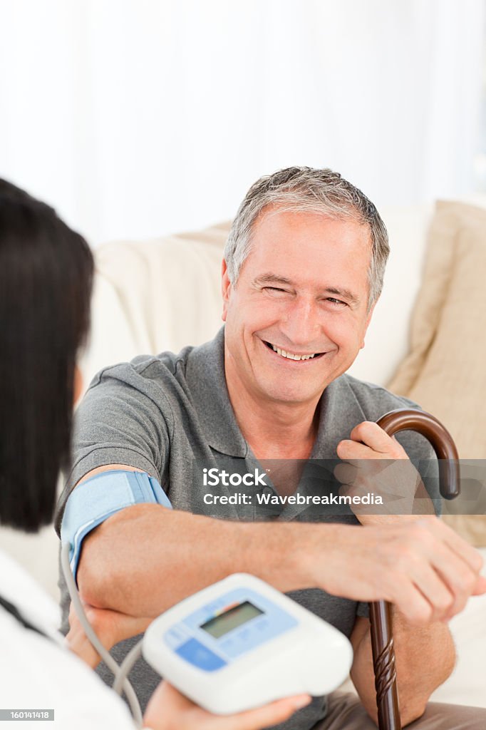 Nurse taking blood pressure of her patient Nurse taking blood pressure of her happy patient Adult Stock Photo