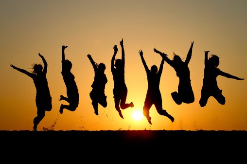 silhouette of friends jumping in sunset at beach