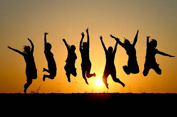 Photo of Silhouette of friends simultaneously jumping