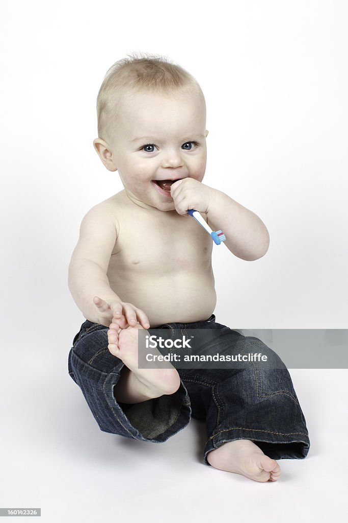 Small boy holding a toothbrush Small nine month old baby boy holding a toothbrush. White Background Baby - Human Age Stock Photo