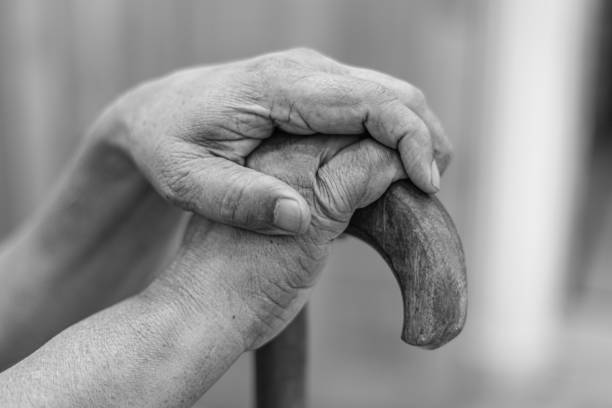 Close up on hands of unknown old Indian man pensioner senior holding cane walking stick while sitting and waiting - real people old age senility concept copy space stock photo